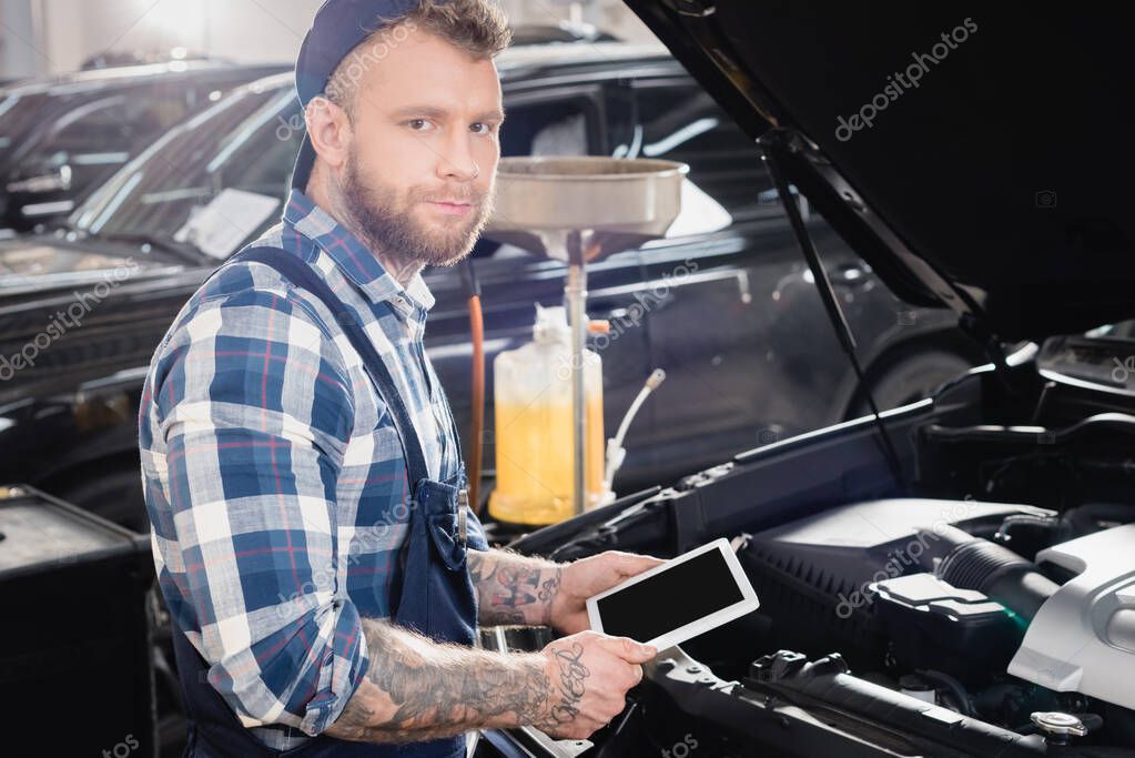 giovane riparatore con tablet digitale vicino al vano motore dell'auto