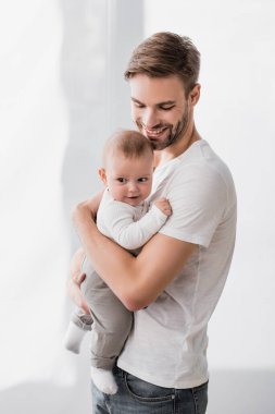 Mutlu baba kollarında neşeli erkek bebek 