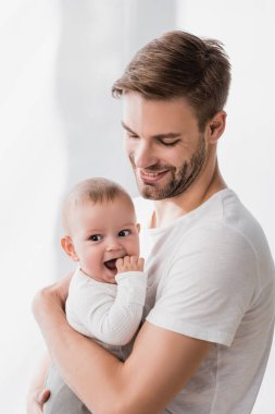 Mutlu baba kollarını tutuyor bebek parmaklarını emiyor 