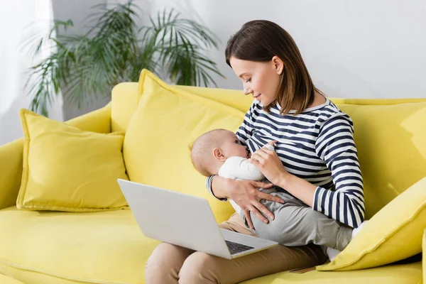 Mulher Segurando Nos Braços Bebê Filho Enquanto Amamenta Perto Laptop — Fotografia de Stock