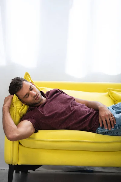 男人睡在家里的黄色沙发上 — 图库照片