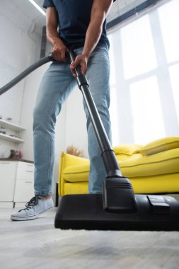 Bulanık arka plandaki adamın ellerinde elektrikli süpürgenin kırpılmış görüntüsü 