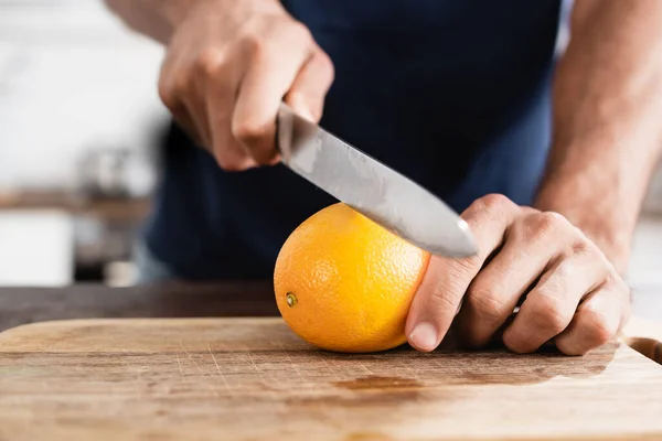 Cropped View Man Holding Orange Knife Wooden Board Blurred Background — Stock Photo, Image