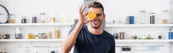 微笑的男人在厨房里 手里拿着一半新鲜的橙子 一面横幅 — 图库照片