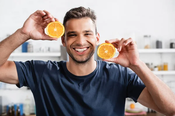 Homem Alegre Segurando Metades Laranja Olhando Para Câmera Cozinha — Fotografia de Stock