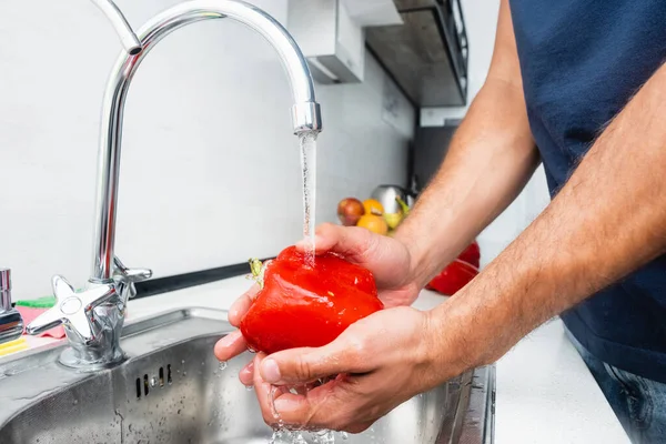 キッチンでベルペッパーを洗う男の作物ビュー — ストック写真