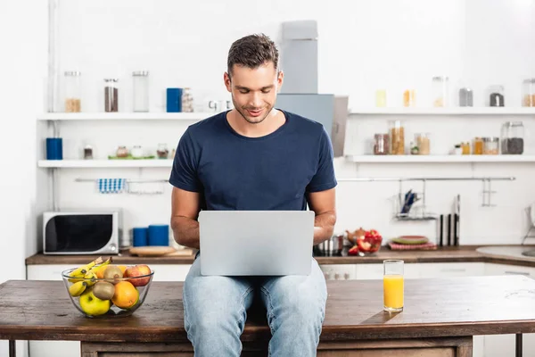 Young Man Using Laptop Glass Orange Juice Fresh Fruits Kitchen — Stock Photo, Image