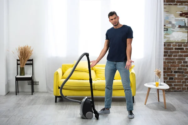 Anak Muda Menunjuk Dengan Tangan Dekat Vacuum Cleaner Ruang Tamu — Stok Foto