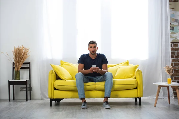 Excited Man Holding Smartphone While Looking Camera Couch — Stock fotografie