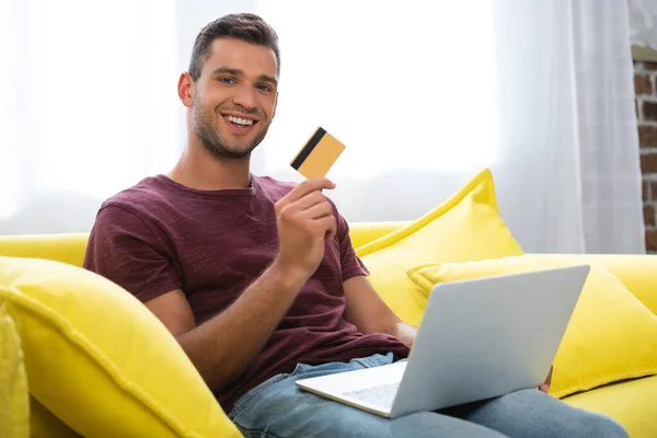 Vrolijke Man Met Credit Card Laptop Wazig Voorgrond Thuis — Stockfoto