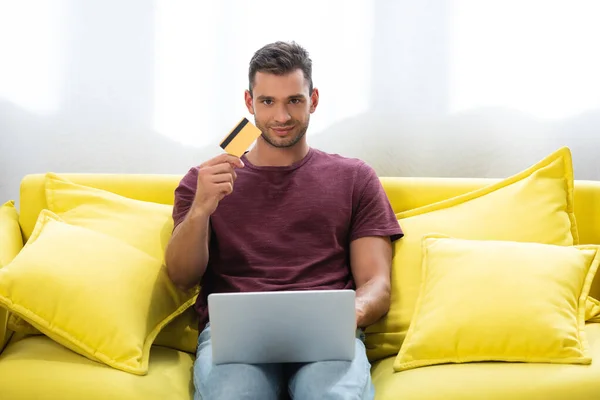 Young Man Looking Camera While Holding Credit Card Laptop Sofa — Foto de Stock