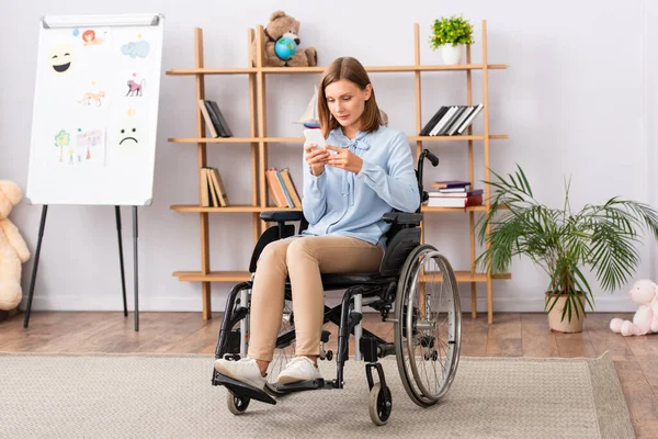 オフィスの車椅子に座っている間 携帯電話上の障害者心理学者のテキストメッセージの完全な長さ — ストック写真