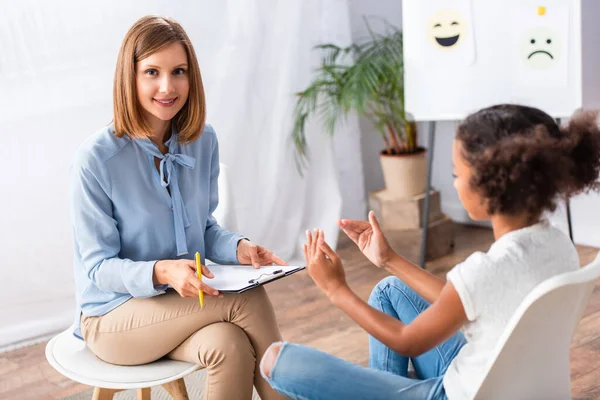 Smiling Psychologist Looking Camera While Sitting African American Girl Gesturing — Stock Photo, Image