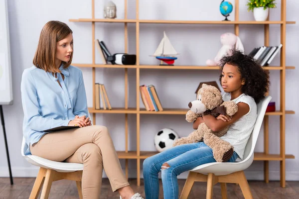 Psicologo Che Parla Con Frustrata Ragazza Afroamericana Abbracciando Orsacchiotto Durante — Foto Stock