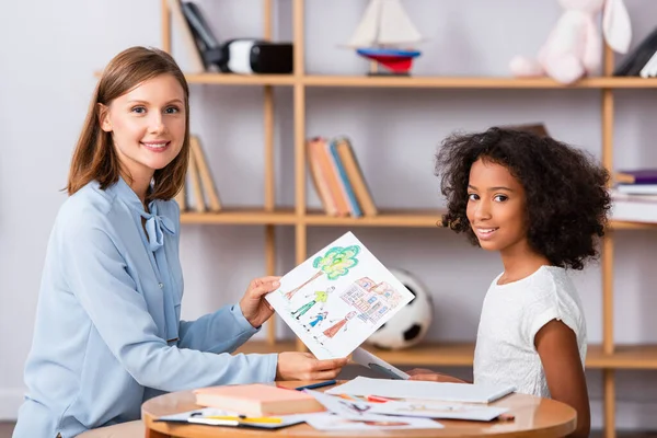 Smiling Multicultural Girl Psychologist Drawing Looking Camera Coffee Table Blurred — Stock Photo, Image