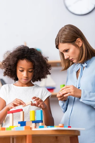 Concentrated Psychologist Looking African American Girl Building Construction Wooden Blocks — Stock Photo, Image