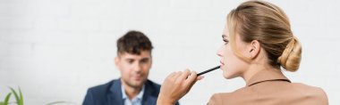 Thoughtful female executive with pen, looking away with blurred colleague on background, banner clipart