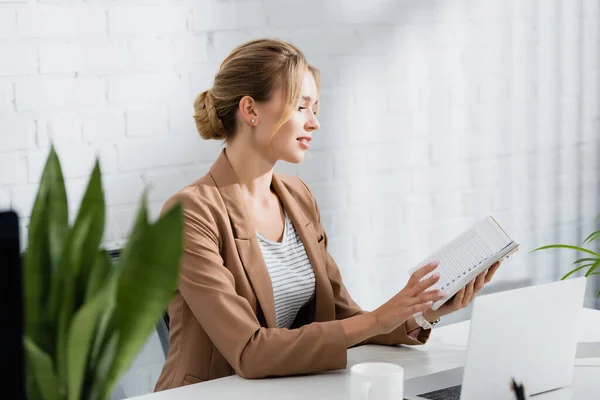 Female Executive Flipping Notebook While Sitting Table Office Blurred Plant — Stock Photo, Image