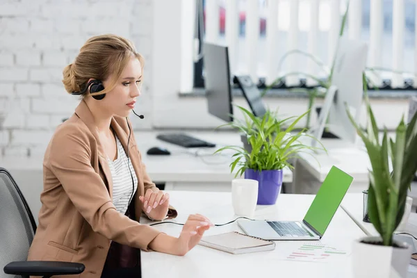 Blond Kvinna Headset Tittar Bärbar Dator Medan Sitter Arbetsplatsen Med — Stockfoto