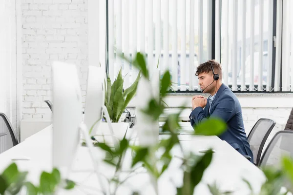 Serious Operator Headset Sitting Workplace Office Blurred Plant Foreground — Stock Photo, Image