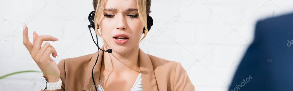 Serious female consultant in headset gesturing on blurred foreground, banner