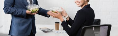 Gülümseyen bir iş kadınının iş yerinden yemek alırken plastik kaseyi alıp iş yerinde pankarta oturması.