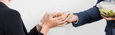Beyaz pankarttaki meslektaşının yemeğiyle plastik kaseyi alan iş kadını görüntüsü.