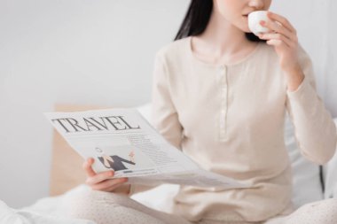 Vitiligo içen, kahve içen ve elinde gazete tutan bir kadın.