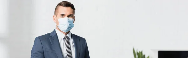 의료용 마스크를 사업가가 배경과 현수막을 보면서 — 스톡 사진