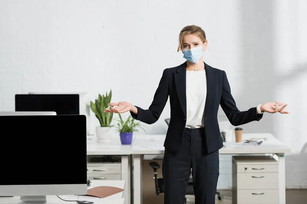 Blonde Businesswoman Medical Mask Gesturing While Looking Camera Standing Workplace — Stock Photo, Image