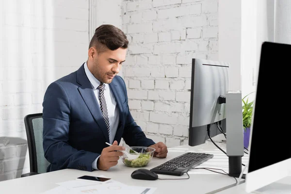 Geschäftsmann Isst Essen Aus Plastikschüssel Während Arbeitsplatz Mit Digitalen Geräten — Stockfoto