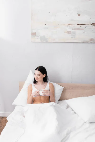 Gelukkig Vrouw Met Vitiligo Vasthouden Kopje Koffie Terwijl Rusten Bed — Stockfoto