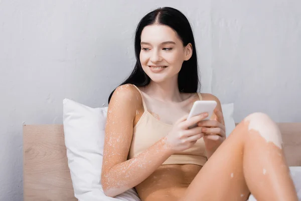 Ευτυχισμένη Γυναίκα Λεύκη Χρησιμοποιώντας Smartphone Στο Υπνοδωμάτιο — Φωτογραφία Αρχείου