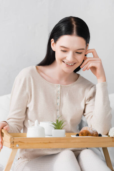 smiling woman with vitiligo looking at tasty breakfast on tray