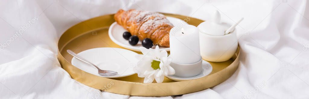 croissant and grapes near candle on breakfast tray in bedroom, banner