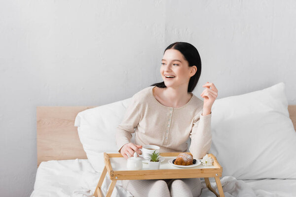 happy woman with vitiligo laughing near breakfast on tray
