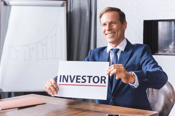 Smiling Businessman Looking Away While Showing Sign Investor Lettering Workplace — Stock Photo, Image