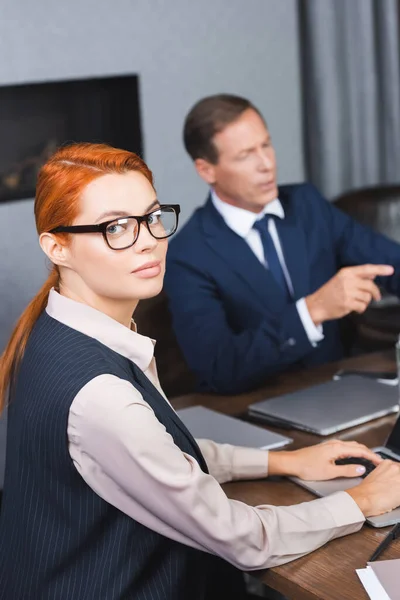 Redhead Businesswoman Eyeglasses Looking Camera While Typing Laptop Blurred Investor — Stock Photo, Image