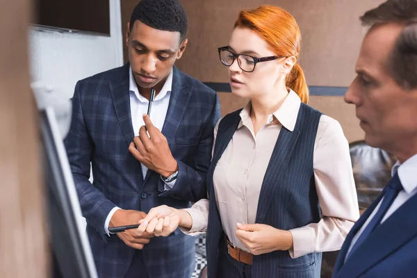 Confident Redhead Businesswoman Pointing Pen Multicultural Colleagues Blurred Foreground — Stock Photo, Image