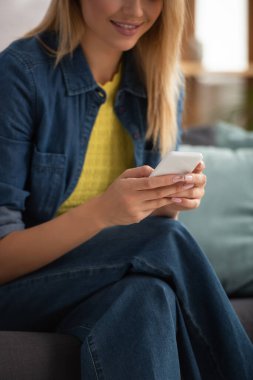 Bulanık arka planda akıllı telefondan mesajlaşan genç bir kadın görüntüsü