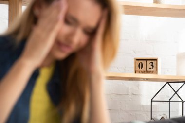 Wooden calendar on shelf with blurred tense woman on foreground clipart