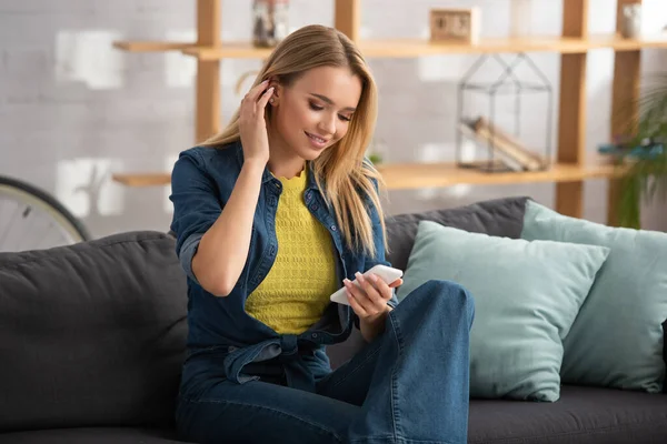 Mujer Joven Feliz Arreglando Cabello Mirando Teléfono Inteligente Sofá Sobre — Foto de Stock