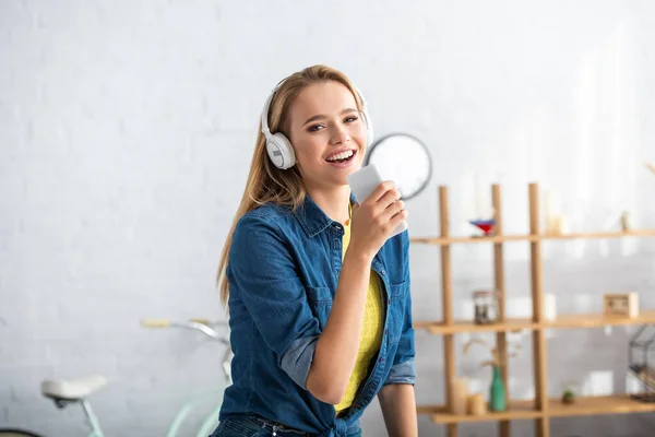 明るいですブロンド女性とともにスマートフォン見ますカメラで歌いながら自宅でぼやけた背景 — ストック写真