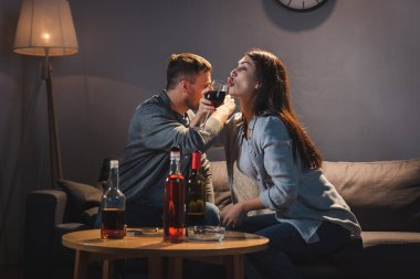 Bir çift alkolik evde viski ve şarap içiyor.