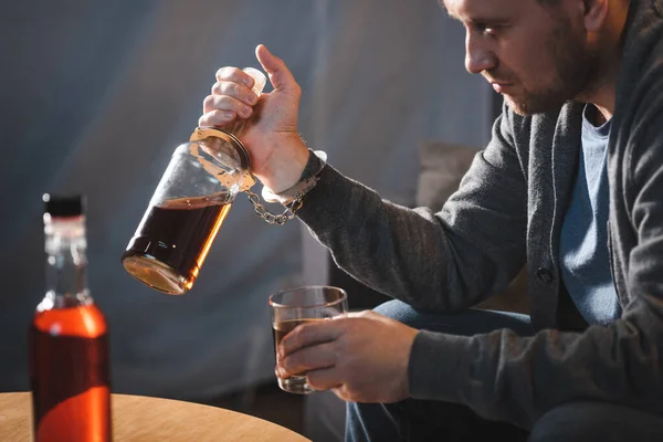 Függő Férfi Megbilincselve Egy Üveg Whiskyhez Homályos Előtér — Stock Fotó