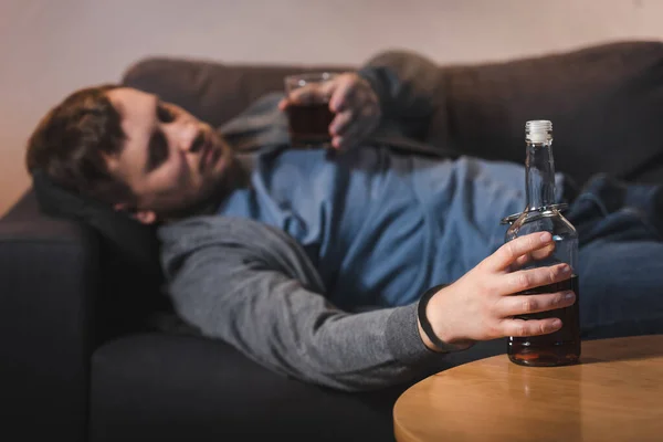 Alkol Bağımlısı Bir Adam Şişeye Kelepçeli Bir Bardak Viskiyle Kanepede — Stok fotoğraf