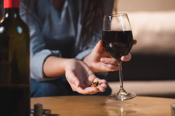 酒精中毒妇女拿着硬币和红酒的选择性焦点 — 图库照片