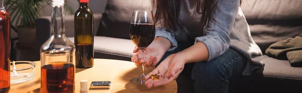 女性手持结婚戒指和酒杯在酒瓶旁边挂在模糊的前景 横幅上的剪影 — 图库照片