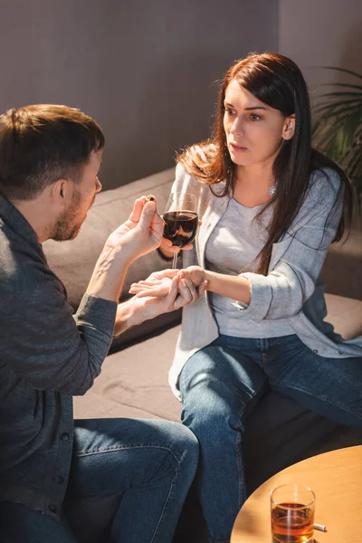 husband giving wedding ring to alcohol-addicted wife holding glass of wine