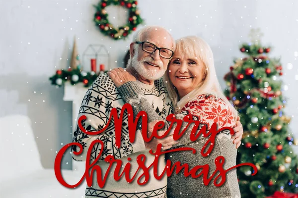 Happy Senior Couple Embracing While Looking Camera Merry Christmas Lettering — Stock Photo, Image